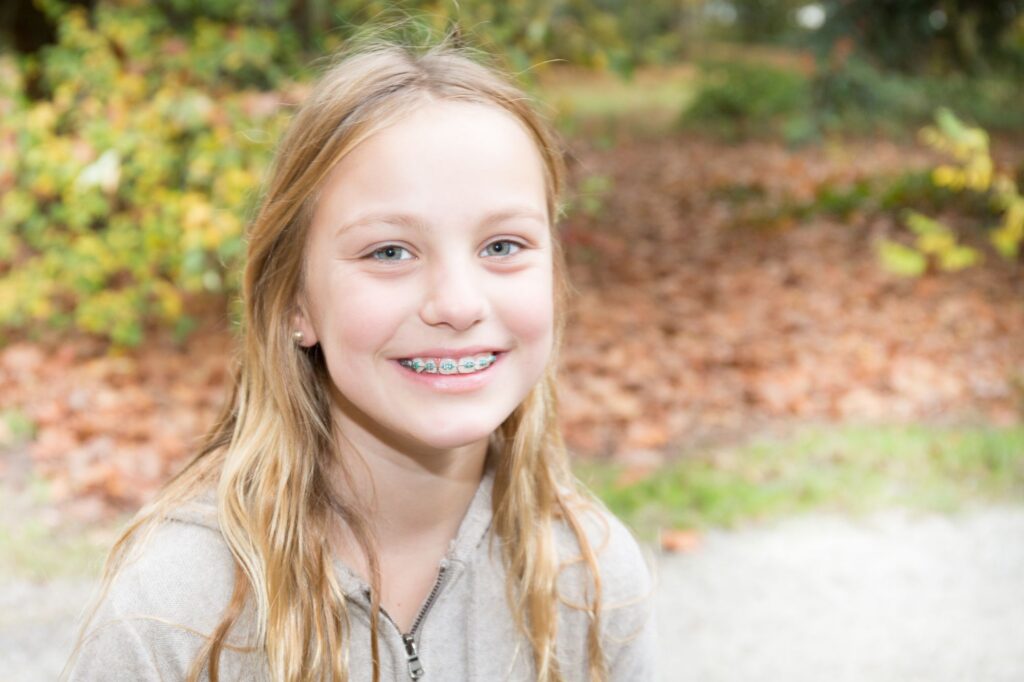 young female patient smiling with metal braces in jericho orthodontics